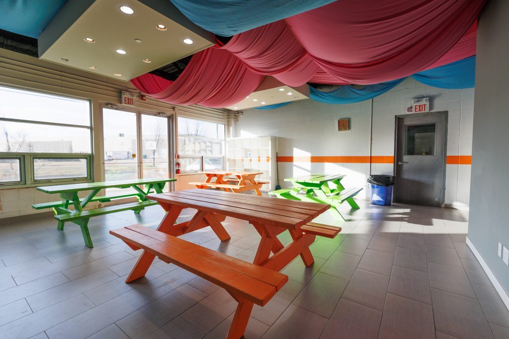 room with green and orange picnic tables