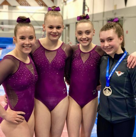 four female gymnastics in club leotards and team jacket